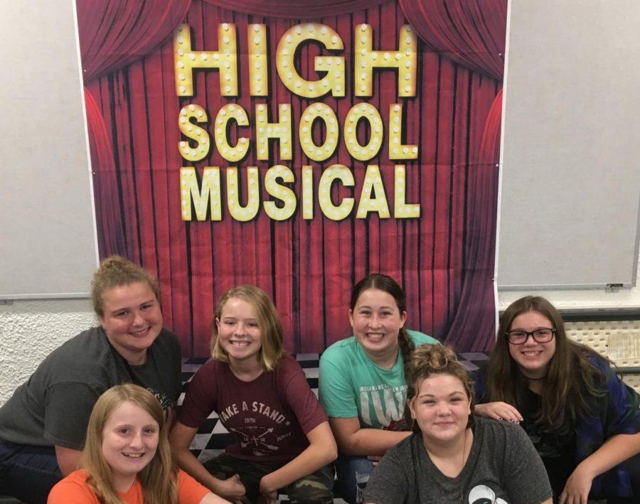 Some members of Drama Club pose in front a sign advertising the musical.