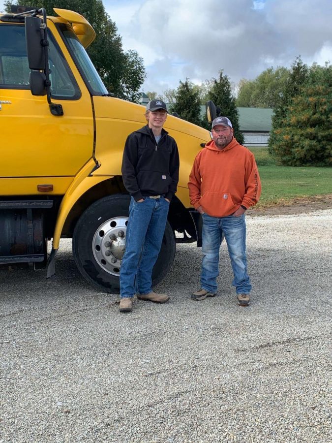 Doug Mears with his farmhand, Jackson Harter, in front of semi tractor. 