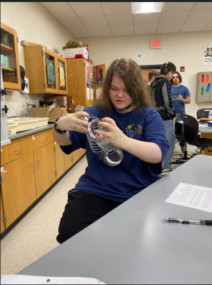 Junior Stephanie Proper plays with a slinky in Earth Space Science.